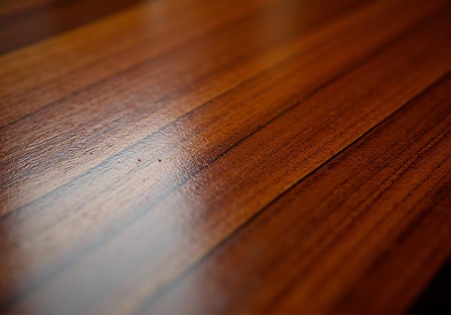 A close-up shot showing the reflective, high-gloss finish of French polishing on a tabletop.